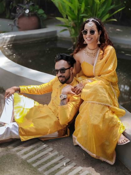 The couple, dressed in matching yellow attire, posing for a portrait during their Haldi ceremony. Their coordinated look adds to the festive theme.