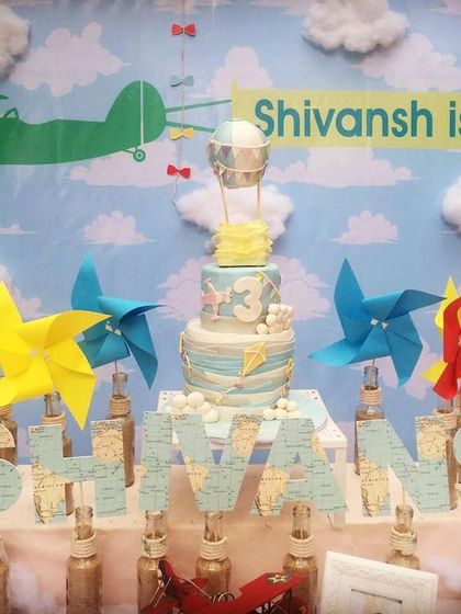 An "up, up and away" travel-themed birthday. The backdrop featured clouds, an airplane, and a hot air balloon to inspire a sense of adventure.