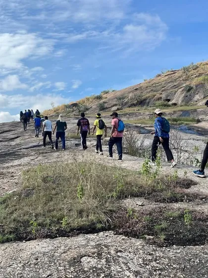 Participants trek up the rocky terrain of Ramanagara to reach the climbing site, a warm-up for the day's activities.