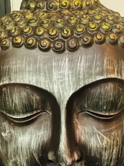 This Buddha statue features a striking metallic finish, with a brushed silver face and gold-accented hair. This finish adds a touch of modern glamour to the traditional form.