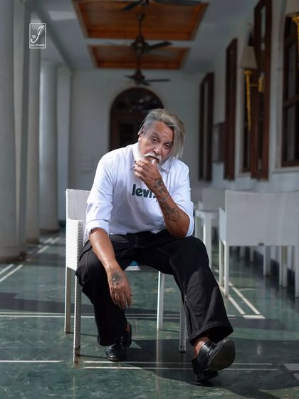 A seated portrait in an outdoor corridor, using the architectural lines and shadows to create a visually interesting composition.