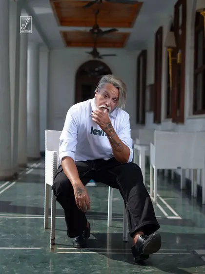 A seated portrait in an outdoor corridor, using the architectural lines and shadows to create a visually interesting composition.