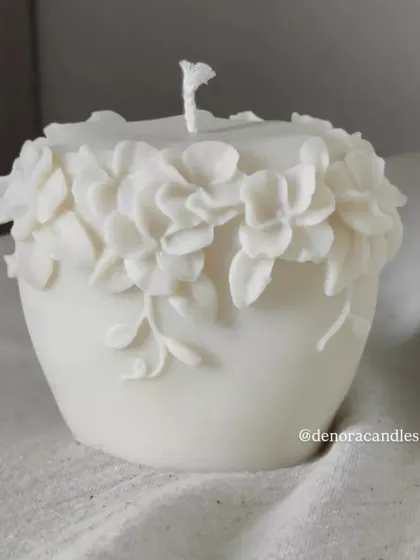 A shorter, pot-shaped floral pillar candle with a crown of 3D flowers.