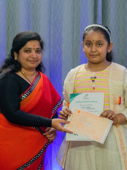 A student proudly holds her certificate after successfully completing her graded music exam.