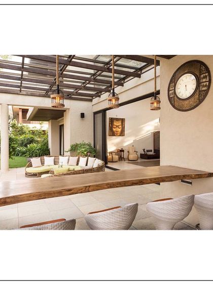An outdoor bar and seating area in our Khandala home. This space blends the surrounding nature with comfort and functionality, featuring a rustic wooden bar top and modern wicker chairs.