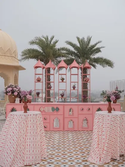 The rooftop bar setup for the 'Pink Jaipuri Bagh' mehendi, with custom pink furniture and patterned tablecloths.