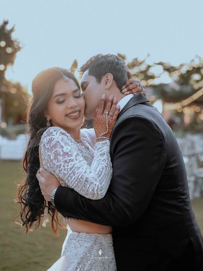 A tender kiss on the cheek, captured at sunset during an outdoor reception. The warm light adds to the romance of the moment.