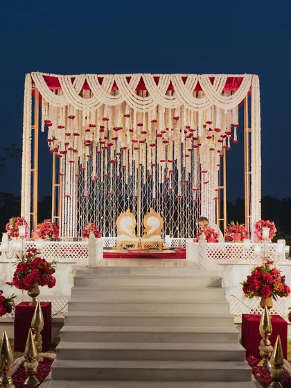 This outdoor mandap combines timeless tradition with regal elegance. We used a structure of cascading mogra and tuberose strings, accented with fresh red roses and suspended temple bells, to create a sacred space that felt both grand and deeply personal under the open sky.