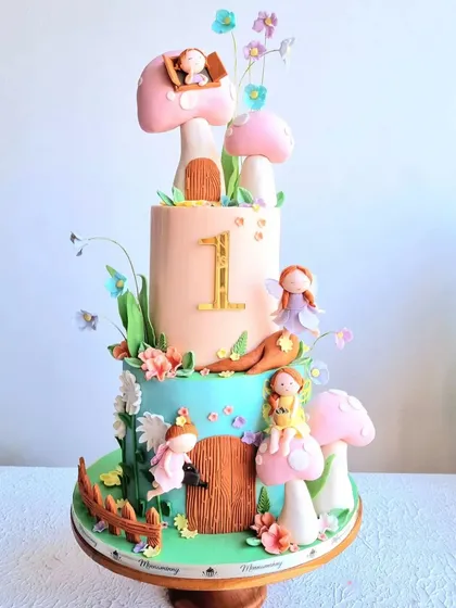 A full view of the two-tiered enchanted garden cake, showing all the fairy figurines.
