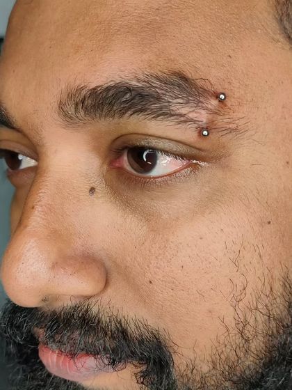A close-up of a freshly done eyebrow piercing. We discuss placement with you to ensure it complements your brow shape and facial features.