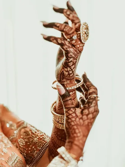An artistic shot of the bride's hands, adorned with intricate henna and bangles. This photo highlights the beauty and tradition of bridal mehndi.