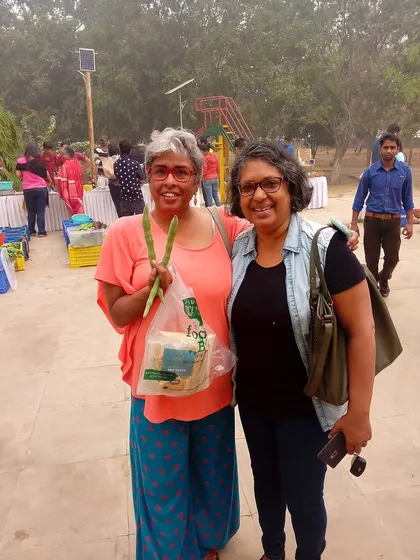 Two happy customers posing with their purchases, including fresh asparagus.