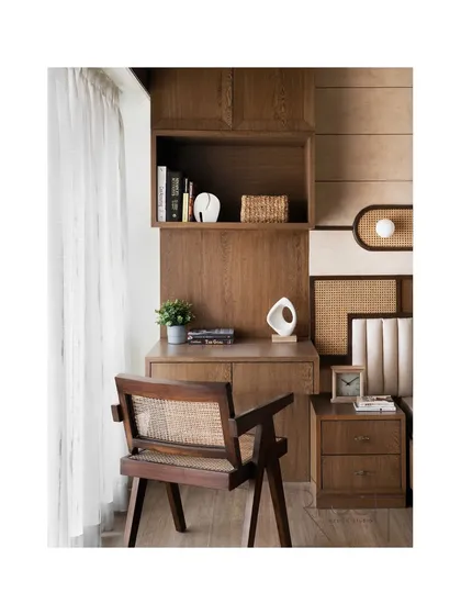 A cozy study corner integrated into the parent's bedroom. The custom desk and chair, made from dark wood and cane, continue the room's vintage, natural aesthetic.