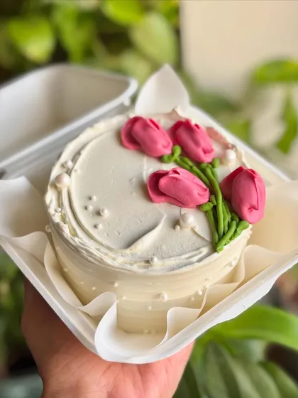 Buttercream blooms and pearly elegance. This minimal bento cake features beautifully piped pink tulips and scattered pearls for a touch of class.