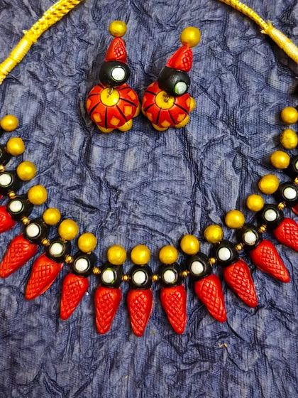 A beautiful spike-style choker necklace in red, black, and white. The set comes with matching jhumka earrings and is a trendy, traditional design.