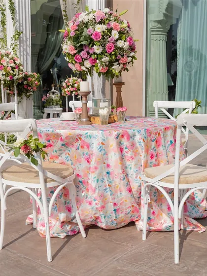 An elegant table setup with a floral printed cloth and a large bouquet of pink and white flowers, perfect for a sophisticated daytime event.