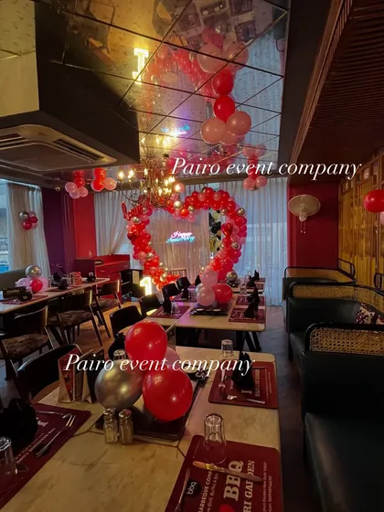 A wide-angle view of the restaurant decorated for a 1st anniversary, showing how the central heart arch and ceiling balloons transform the entire space.