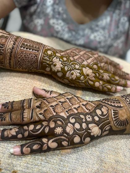 A beautiful shot of two different mehandi styles. One hand has a floral vine pattern, while the other has a more traditional filled design.
