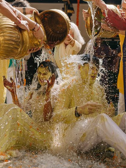 The grand finale of the Haldi, with the couple being showered with water. This high-energy shot is full of laughter and surprise, a perfect memory of their joyful celebration.