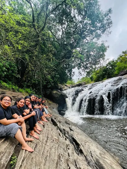 Our group sitting on a large rock, dipping their feet in the stream above a waterfall.