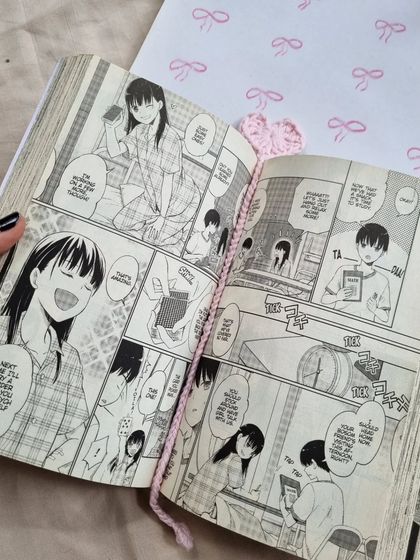 Our crochet heart bookmark in action, keeping the page in a manga. It's a delicate and charming way to mark your progress.