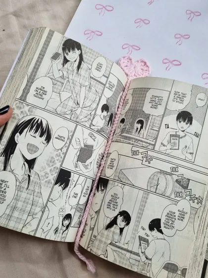 Our crochet heart bookmark in action, keeping the page in a manga. It's a delicate and charming way to mark your progress.
