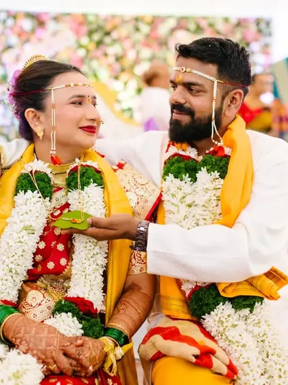 A sweet, candid moment between the couple during their ceremony, with the groom playfully offering a betel leaf to his bride.