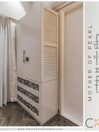 This angle highlights the contrast between the clean white finish and the intricate mother of pearl tile drawers. The louvered shutter on the side adds another layer of classic detail.