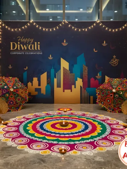 This corporate Diwali photo corner combines modern and traditional elements. A custom backdrop featuring a city skyline is paired with a vibrant, handcrafted rangoli and ornate Rajasthani umbrellas, creating a unique and beautiful spot for employees to capture festive memories.