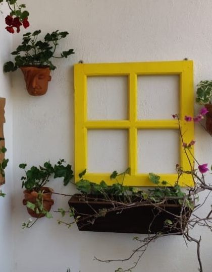 I love getting creative with wall spaces. For this balcony, I used a bright yellow repurposed window frame as a centerpiece, surrounded by terracotta wall planters to turn a plain wall into a vibrant vertical garden.