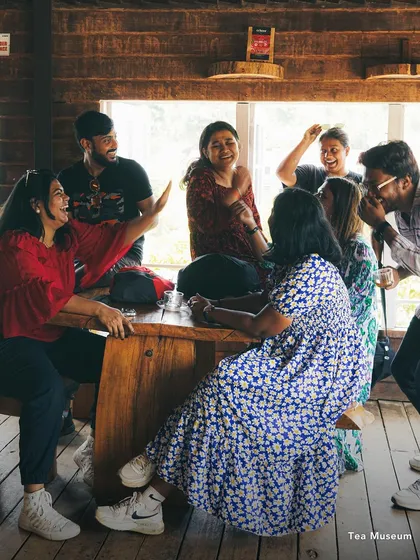 A group of friends laughing and talking at a tea museum. My trips are about these candid moments of connection and shared experiences.