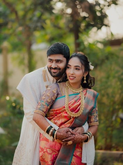 A classic couple portrait from an engagement shoot. The groom embraces the bride from behind as they both look away, creating a serene and romantic image.