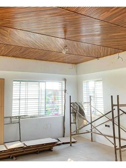 On-site at a residence, with the teak wood ceiling panels installed. The scaffolding shows that the space is still transforming, but the warmth of the wood is already present.