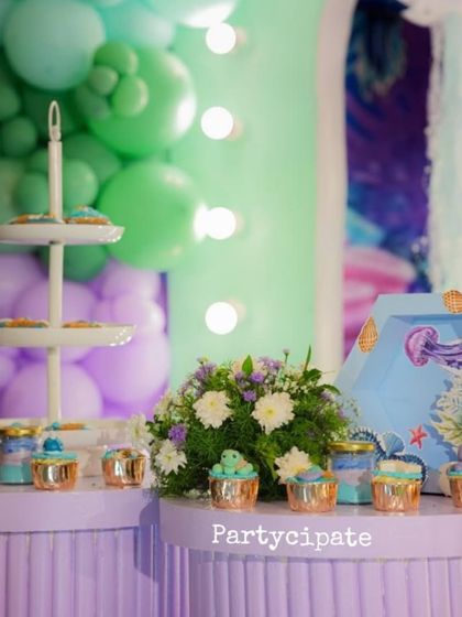 Themed cupcakes and desserts were displayed on a table decorated with a beautiful balloon garland, all in the party's purple and teal color scheme.