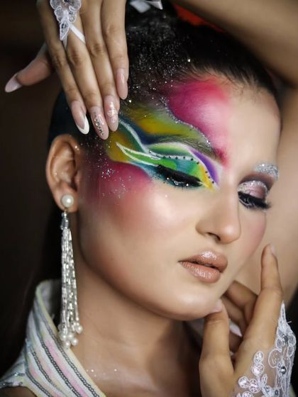 A close-up of the colorful makeup, showing the blend of pink, green, and blue with glitter accents.