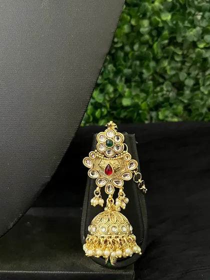 A traditional jhumka with a floral top and a bell adorned with kundan stones.