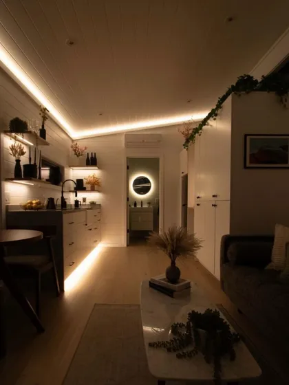 The ambient lighting in this modular home creates a cozy and sophisticated atmosphere at night. The warm glow highlights the clean lines and modern furnishings of the interior.