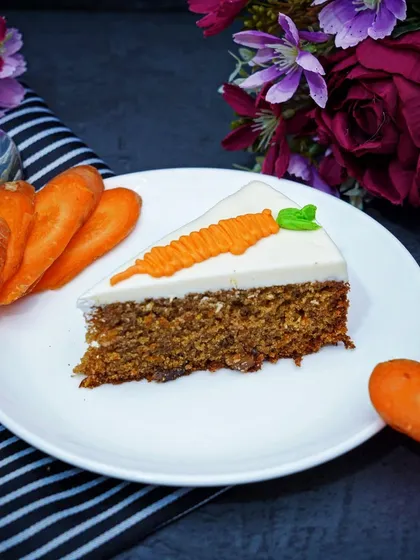 A clean, simple shot of a slice of carrot cake on a white plate. This classic presentation focuses on the product itself, making it ideal for a menu or online store.