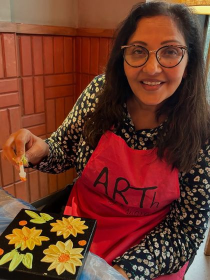 A participant enjoying the process of creating a floral texture art piece. The use of palette knives to shape the petals is a fun and engaging technique.