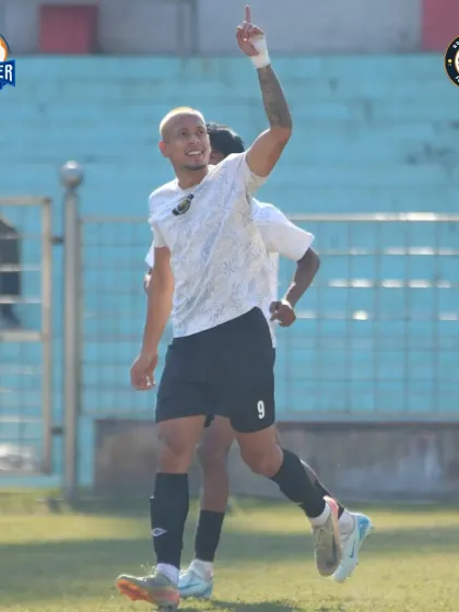 The goalscorer celebrates, pointing to the sky. A moment of individual brilliance contributing to the team's success.