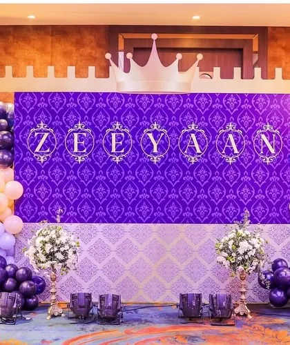 A royal celebration fit for a little prince. This majestic backdrop uses a rich purple damask pattern, a castle silhouette, and personalized lettering for "Zeeyan," framed by elegant balloon arches. This setup showcases my ability to create a sophisticated and regal ambiance.