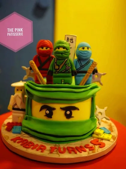 A Ninjago-themed cake for Kabir's birthday. This cake features the face of the Green Ninja and is topped with LEGO-style ninja figures.