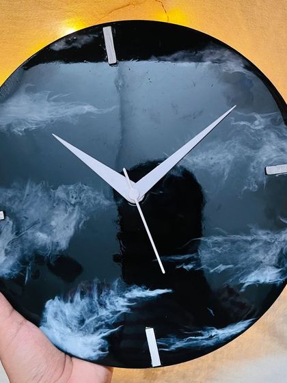 A close-up of a finished galaxy-themed resin clock, showcasing the beautiful black and white swirls that mimic cosmic clouds. This is a functional piece of art you can make yourself.