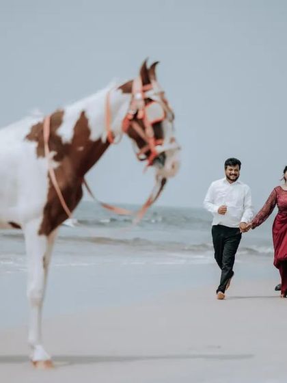 A wide shot of a couple walking on the beach with a horse, capturing the full scene and the romantic atmosphere of their pre-wedding shoot.