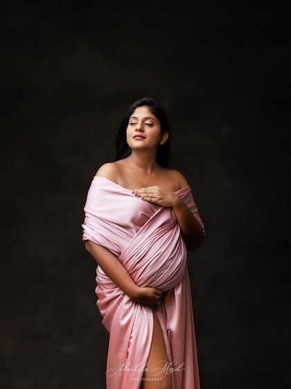 A quiet, introspective moment captured in profile, with the mother-to-be wrapped in soft pink satin.