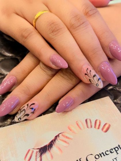 An elegant design on long almond nails. The solid mauve base is complemented by accent nails with intricate, hand-painted black patterns.