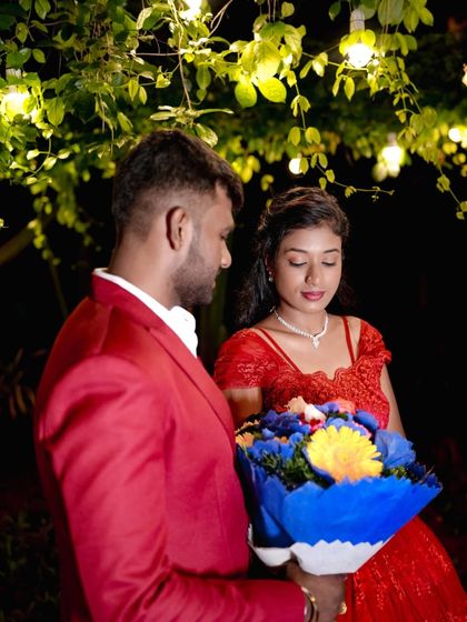 A romantic moment with a bouquet of flowers under a canopy of lights in the garden.