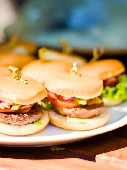 Another angle of our popular mini burgers, showcasing the fresh lettuce, tomato, and onion. We believe in using the finest ingredients to craft global tastes that elevate your event.
