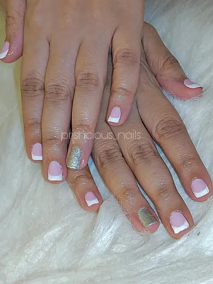 A classic French manicure with a silver glitter accent nail, all done with gel polish on the client's natural nails.