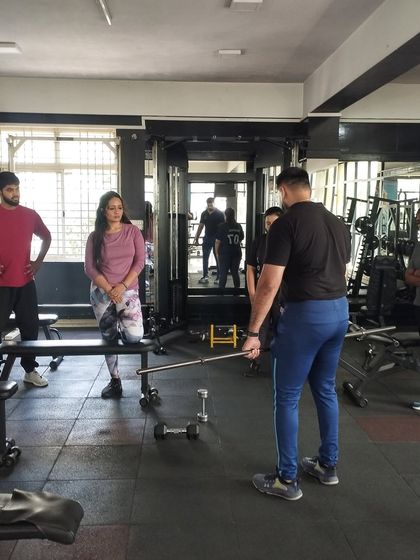 A trainer provides instruction on using a barbell, ensuring students understand the nuances of different grips and stances.